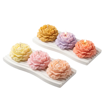 MieleGifts soy wax peony flower candles in pastel colors arranged on white ribbed trays with two candles lit.