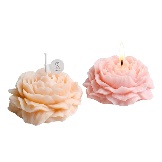 MieleGifts peony-shaped soy wax candles in soft pink and peach, one unlit and one burning on a white background.